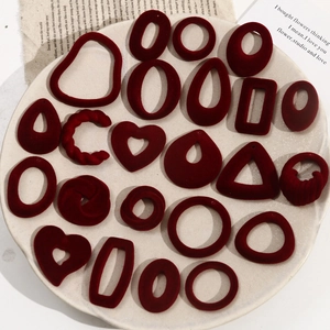 Close-up of burgundy flocked geometric earring pendants with heart and drop shapes