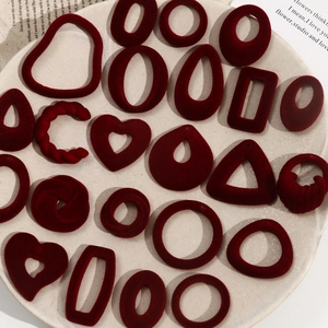 Close-up of burgundy flocked geometric pendants for DIY jewelry on a white plate