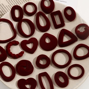 Detailed view of burgundy flocked geometric earring pendants in various shapes in a tray