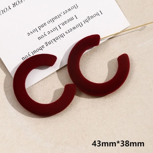 Detail of burgundy velvet C-shaped hoop earrings with soft flocked texture and golden needles