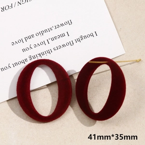Close-up of vintage burgundy flocked oval earrings with gold metal posts and matte texture