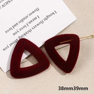 Burgundy flocked triangle drop earrings with gold metal posts on a beige textured surface