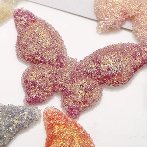 Detailed macro view of large resin butterfly charms with sparkly crystal resin texture