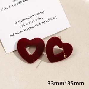 Close-up of burgundy flocked heart earring with gold metal hook on romantic background