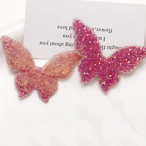 Macro detail of large butterfly resin charms with sparkling pink and purple sequins