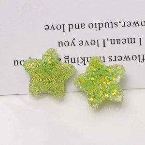 Macro shot of 20mm green resin stars with sugar sequins and glitter for DIY jewelry making