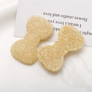 Dettaglio di ciondoli a fiocco in resina DIY con paillettes lucide e trama effetto ghiaccio