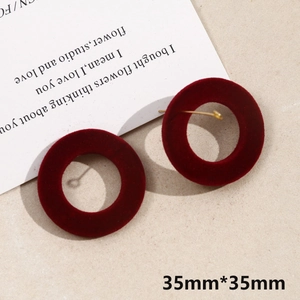 Detailed view of 35mm burgundy flocked round earrings with gold pins on warm grey background
