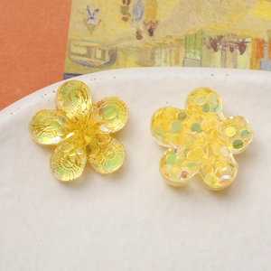 Macro shot of yellow translucent flower charms with iridescent sequins for jewelry DIY