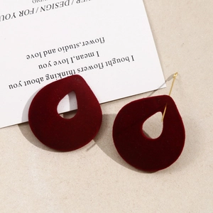 Detailed macro view of teardrop velvet earrings with golden metal studs in burgundy