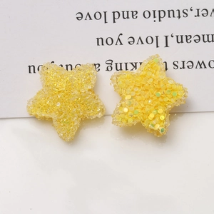 Detailed macro of 20mm lemon yellow resin star charms with glitter and ice texture