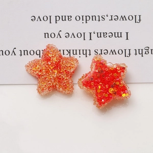 Detailed macro view of 20mm resin stars with orange and gold glitter for DIY crafts