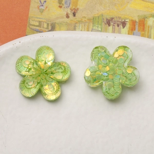 Macro view of emerald green resin flower earrings with sparkling gold and green sequins