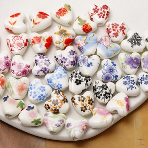 Macro view of heart-shaped ceramic beads with hand-painted floral patterns for DIY jewelry