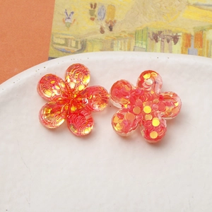 Macro shot of two translucent red resin flower charms with colorful laser sequins