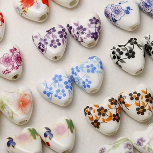 Hand-painted heart-shaped ceramic beads with floral patterns and vertical holes for DIY jewelry