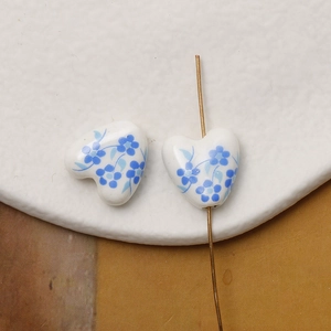Detailed macro view of heart-shaped ceramic beads with blue floral hand-painted pattern