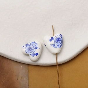Macro shot of heart-shaped ceramic beads with blue floral patterns and drill hole