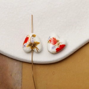 Macro shot of heart-shaped ceramic bead with hand-painted floral pattern and center hole