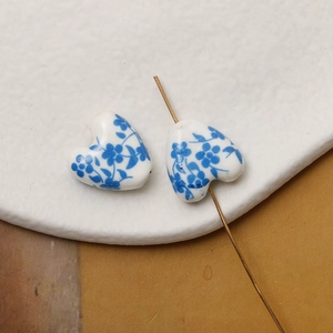 Macro shot of a heart-shaped ceramic bead with blue floral patterns for DIY jewelry