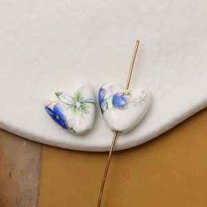 Detail of heart-shaped ceramic beads with blue floral patterns for DIY jewelry making