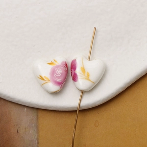 Detailed macro view of heart-shaped white ceramic beads with floral patterns for jewelry DIY