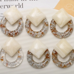 Detailed close-up of handmade geometric resin earrings with silver foil and marble patterns