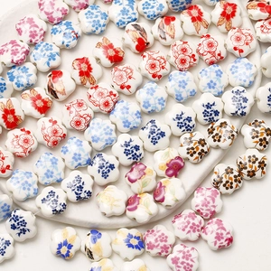 Macro detail of colorful ceramic flower beads with hand-painted floral patterns for DIY jewelry