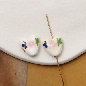 Macro detail of hand-painted heart ceramic beads with lotus flower patterns and gold trim
