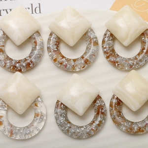 Detail of marble pattern resin earrings with silver foil in transparent round hoops