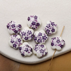 Macro shot of white and purple hand-painted ceramic five-petal flower beads with straight hole