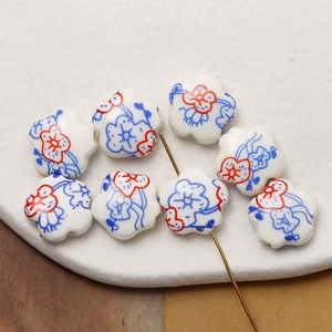 Macro shot of hand-painted floral ceramic beads with white background and red accents