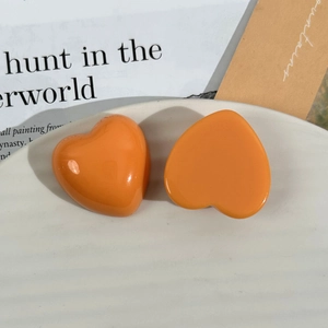 Macro detail of bright orange resin heart charms on a white decorative wave tray