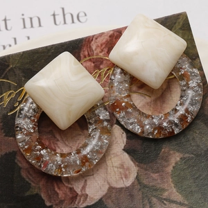 Detail of square marble pattern and round resin earrings with embedded silver foil