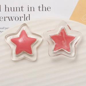 Close-up of glossy double-layer resin star charms on minimalist white textured background