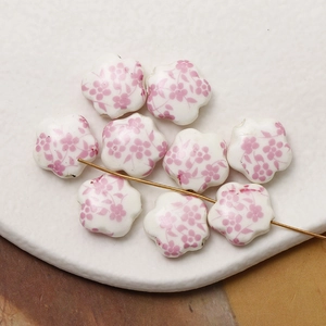 Close-up of pink floral ceramic beads with holes for DIY jewelry making and crafting