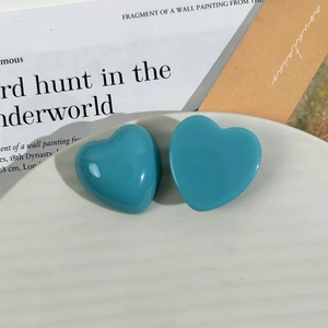 Macro shot of turquoise heart-shaped resin charms on a white textured ceramic tray