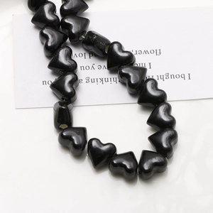 Close-up of glossy black heart-shaped ceramic beads for DIY jewelry making and crafts