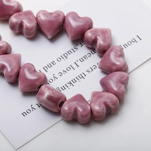 Detailed view of glossy mauve ceramic heart beads for DIY jewelry and earring making