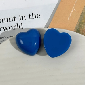 Close-up of glossy deep blue resin heart charms on a white ceramic plate for DIY crafts