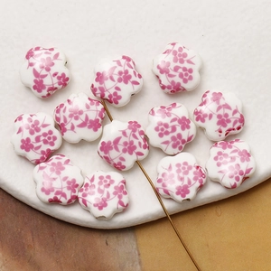 Detail view of handmade ceramic five-petal flower beads with pink plum blossom patterns
