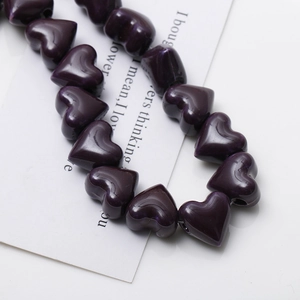 Macro shot of dark purple heart-shaped ceramic beads with marble texture and side holes