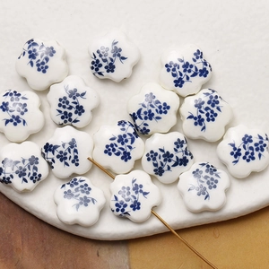 Macro detail of ceramic flower beads with blue floral glaze and golden threading pin