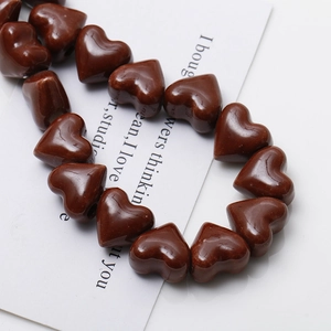 Macro view of glossy caramel ceramic heart beads with holes for DIY jewelry making