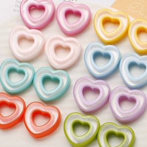 Flat lay of colorful hollow heart resin charms for DIY earrings on a white tray