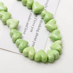 Macro shot of light green ceramic heart beads with marble texture for DIY jewelry making