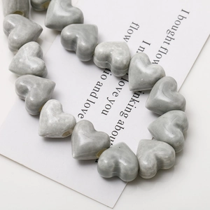 Macro view of heart-shaped grey ceramic beads with marble texture and vertical holes