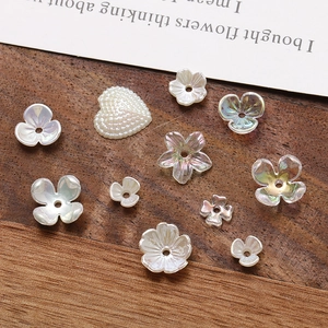 Macro view of pearlescent acrylic flower and heart beads for DIY jewelry on wood