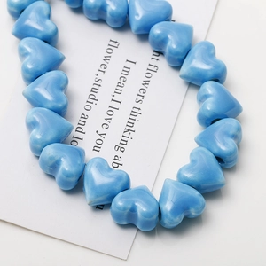 Macro shot of blue heart-shaped ceramic beads with glossy glaze on white display card
