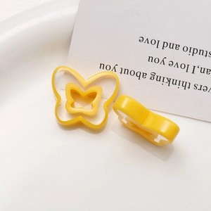 Close-up of yellow resin butterfly charms with hollow design on white tray